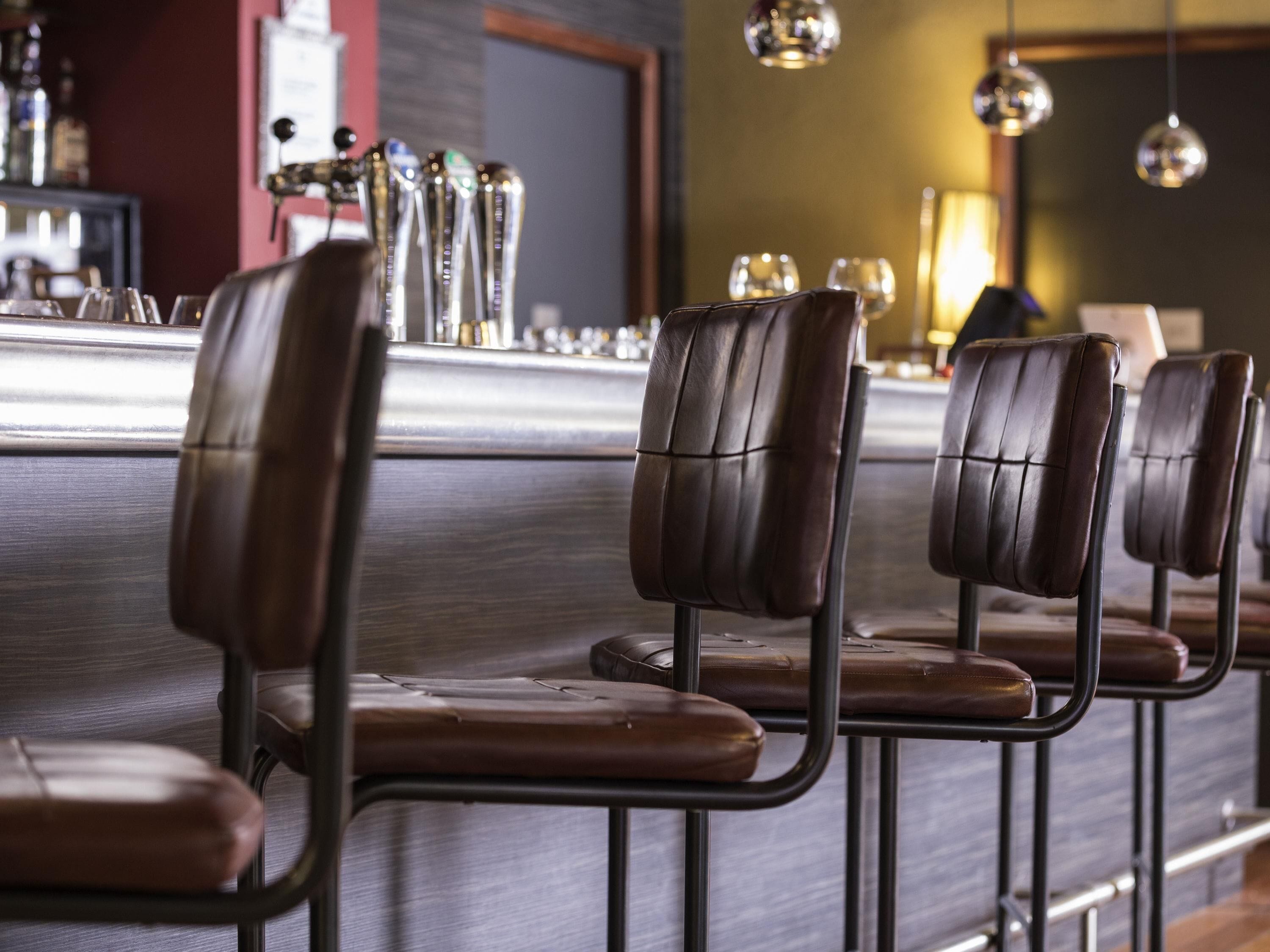A bar area with leather chairs and a bar counter with multiple taps.