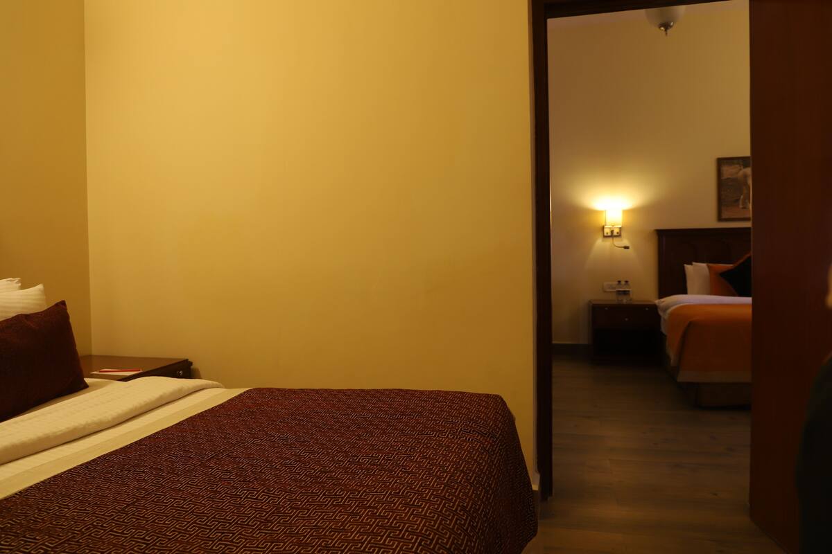 A hotel room with a bed, a nightstand, and a wall-mounted lamp.