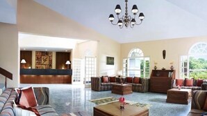 A spacious lobby with a reception desk, sofas, and a chandelier. - Gir Serai - IHCL SeleQtions (Mendarda)