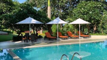 Alberca al aire libre, sombrillas en la alberca y camastros