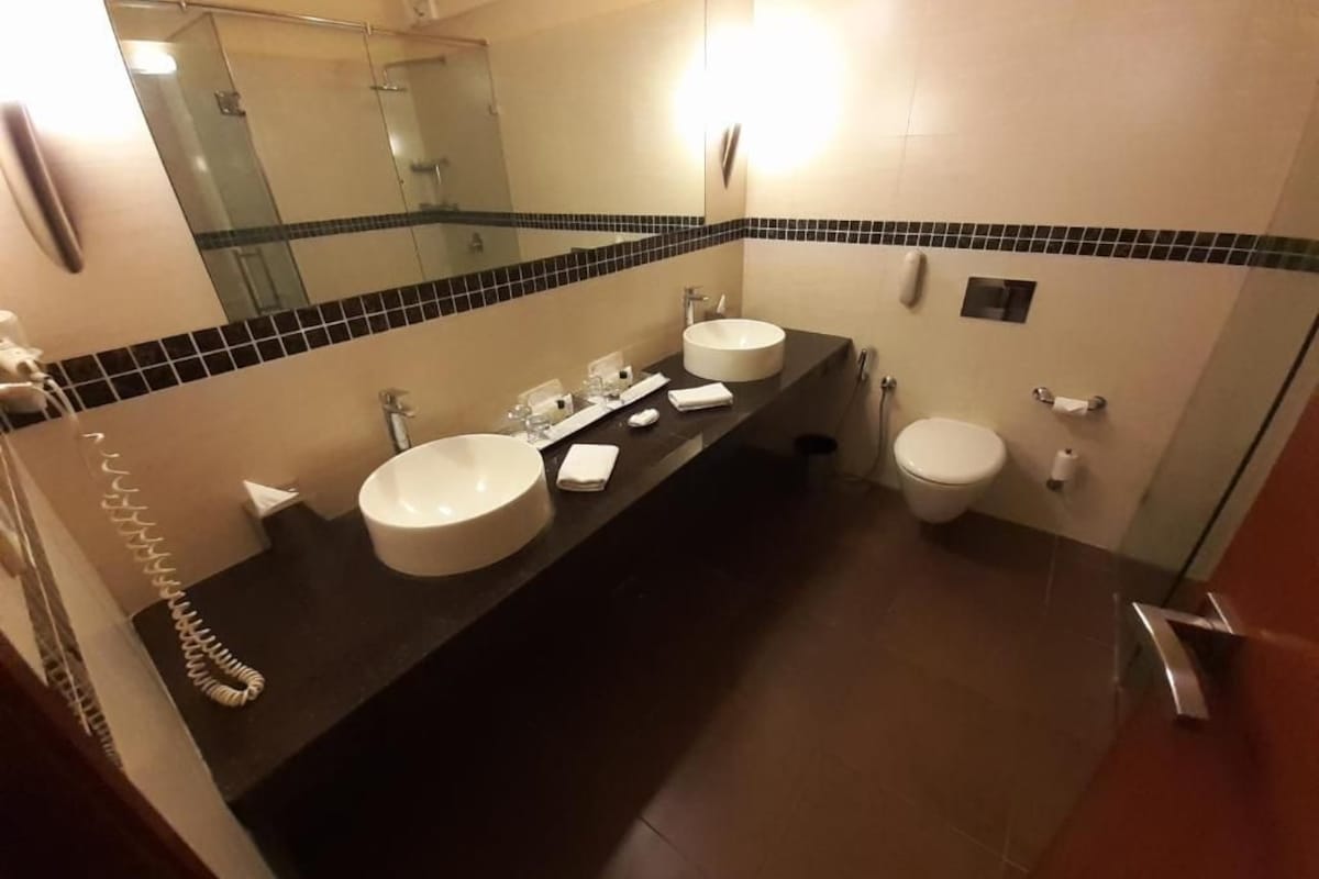 A bathroom with two sinks, a toilet, a mirror, and a shower.