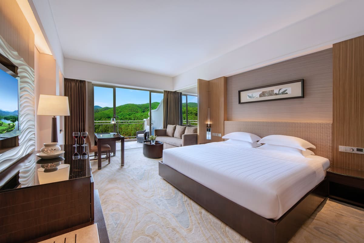 Una habitación de hotel con una cama grande, un sofá, un comedor y vistas al exterior.