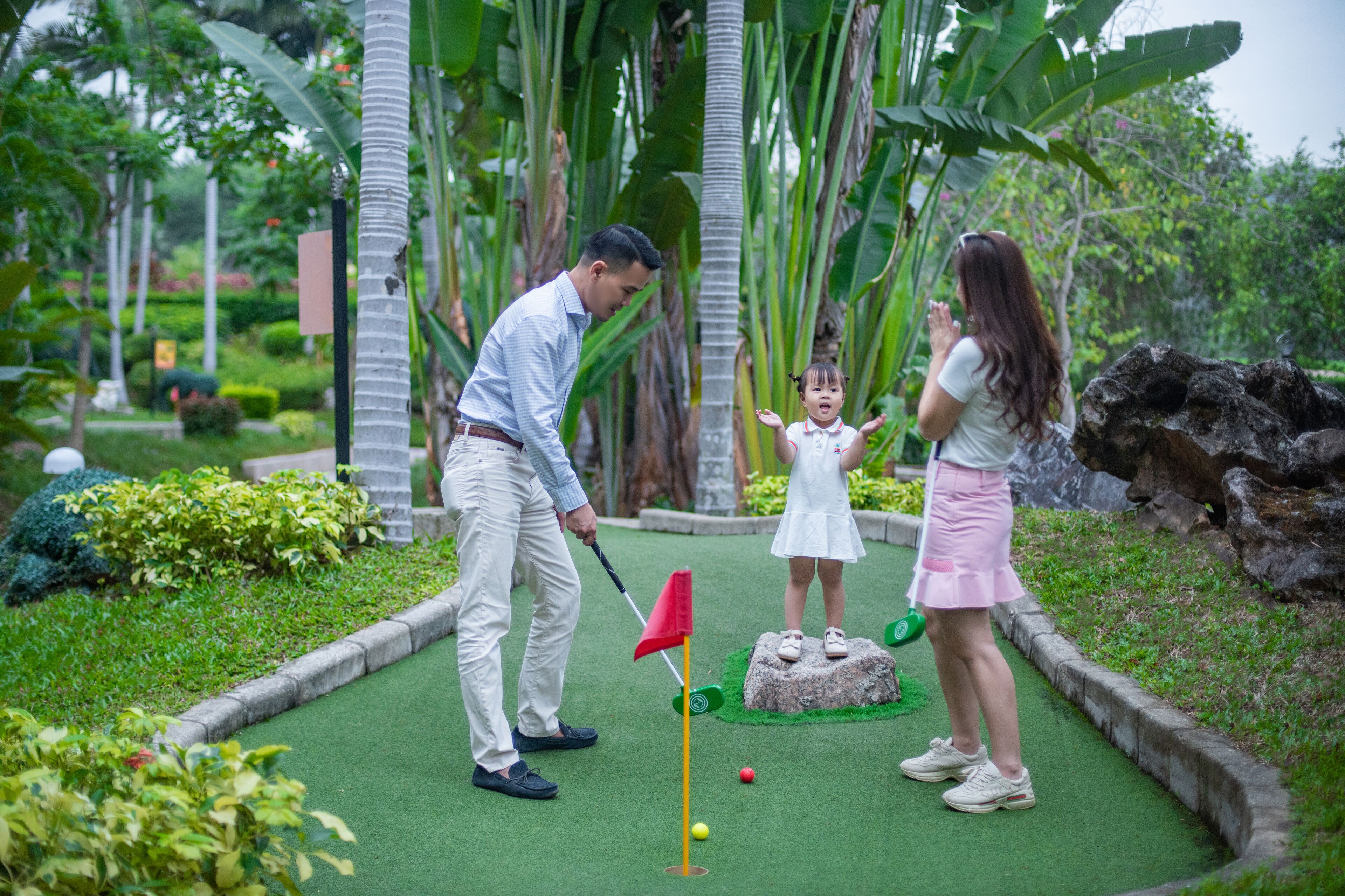 A golf course with a putting green, a flagstick, and a rock with a hole.