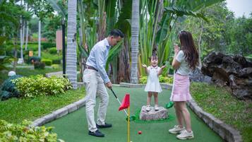 A golf course with a putting green, a flagstick, and a rock with a hole.