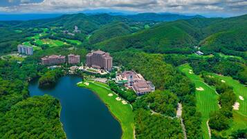 An aerial view of a golf course with multiple buildings, a lake, and surrounding hills.
