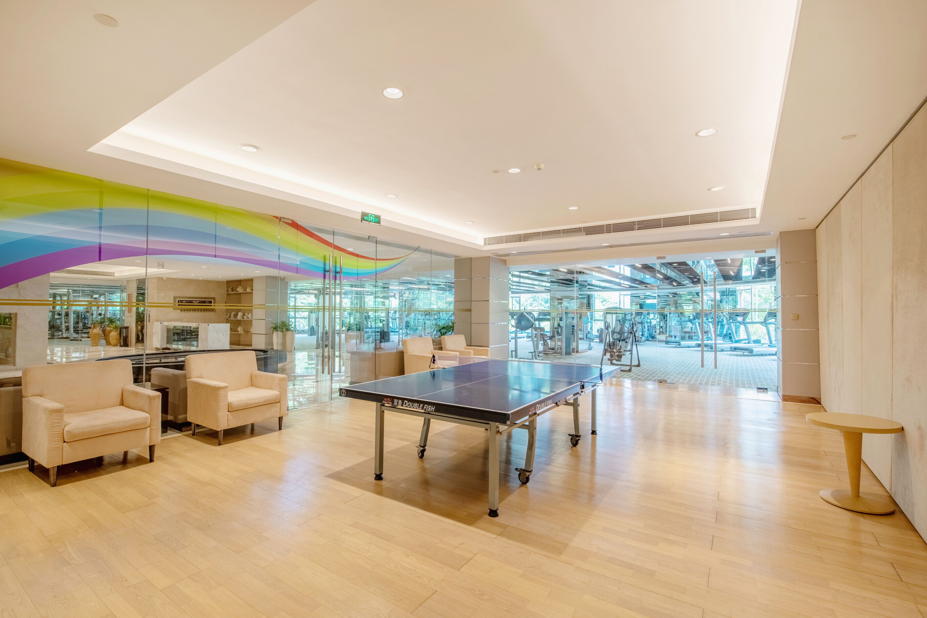 Un grand espace intérieur comprenant une table de ping-pong, plusieurs chaises et un mur en verre.