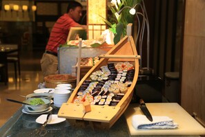 Une présentation de sushis comprenant différents types de sushis, disposés sur un présentoir en bois en forme de bateau.