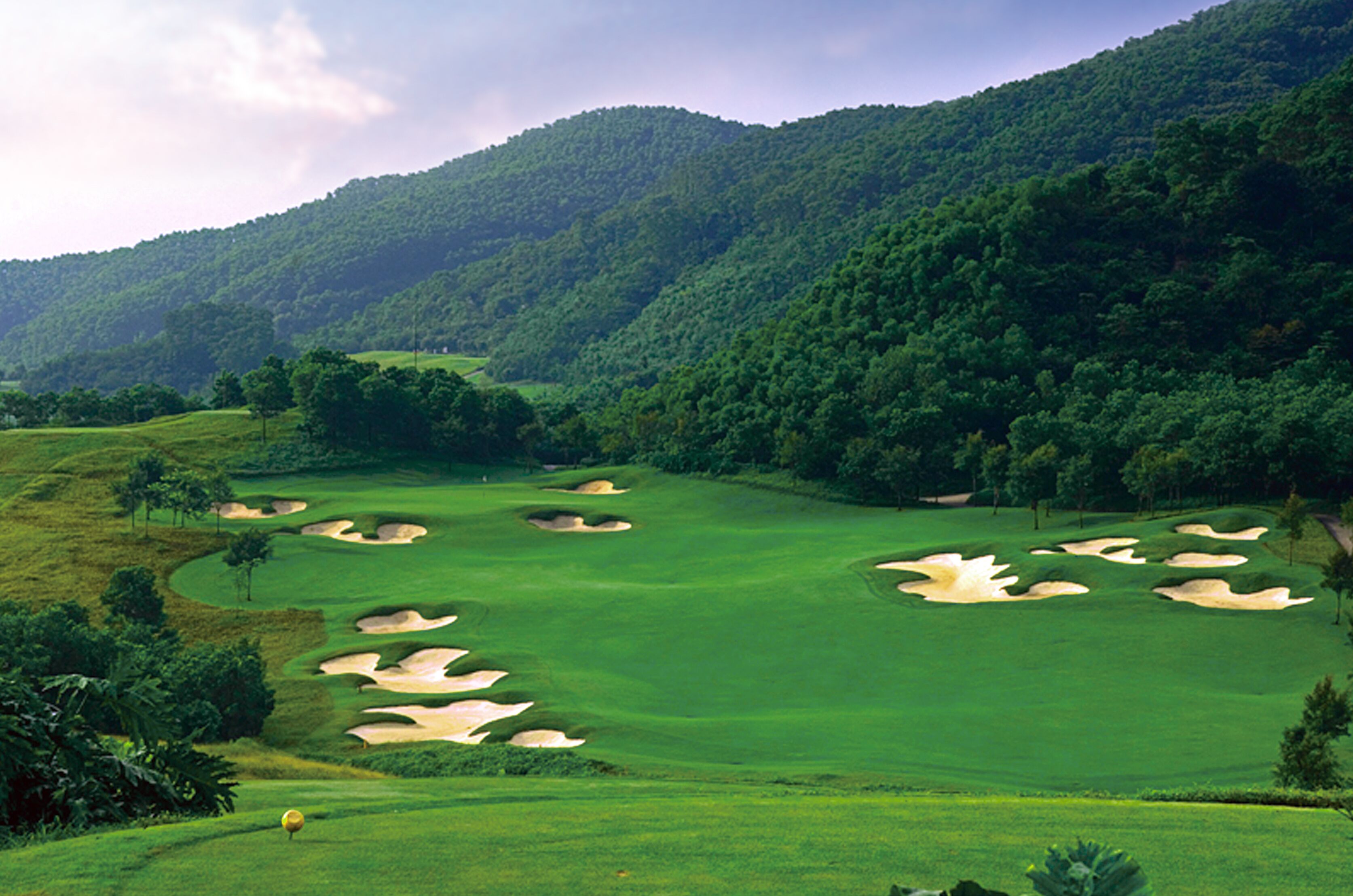 A golf course with sand bunkers and lush greenery.