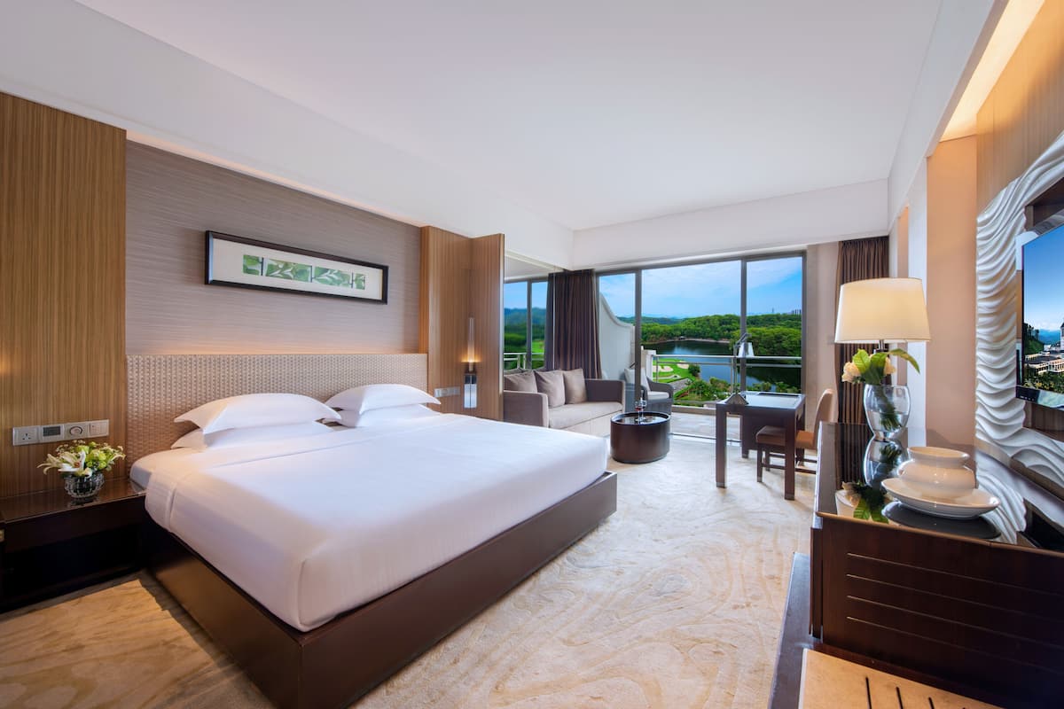 Habitación de hotel con una cama grande, un escritorio y vista a un lago.