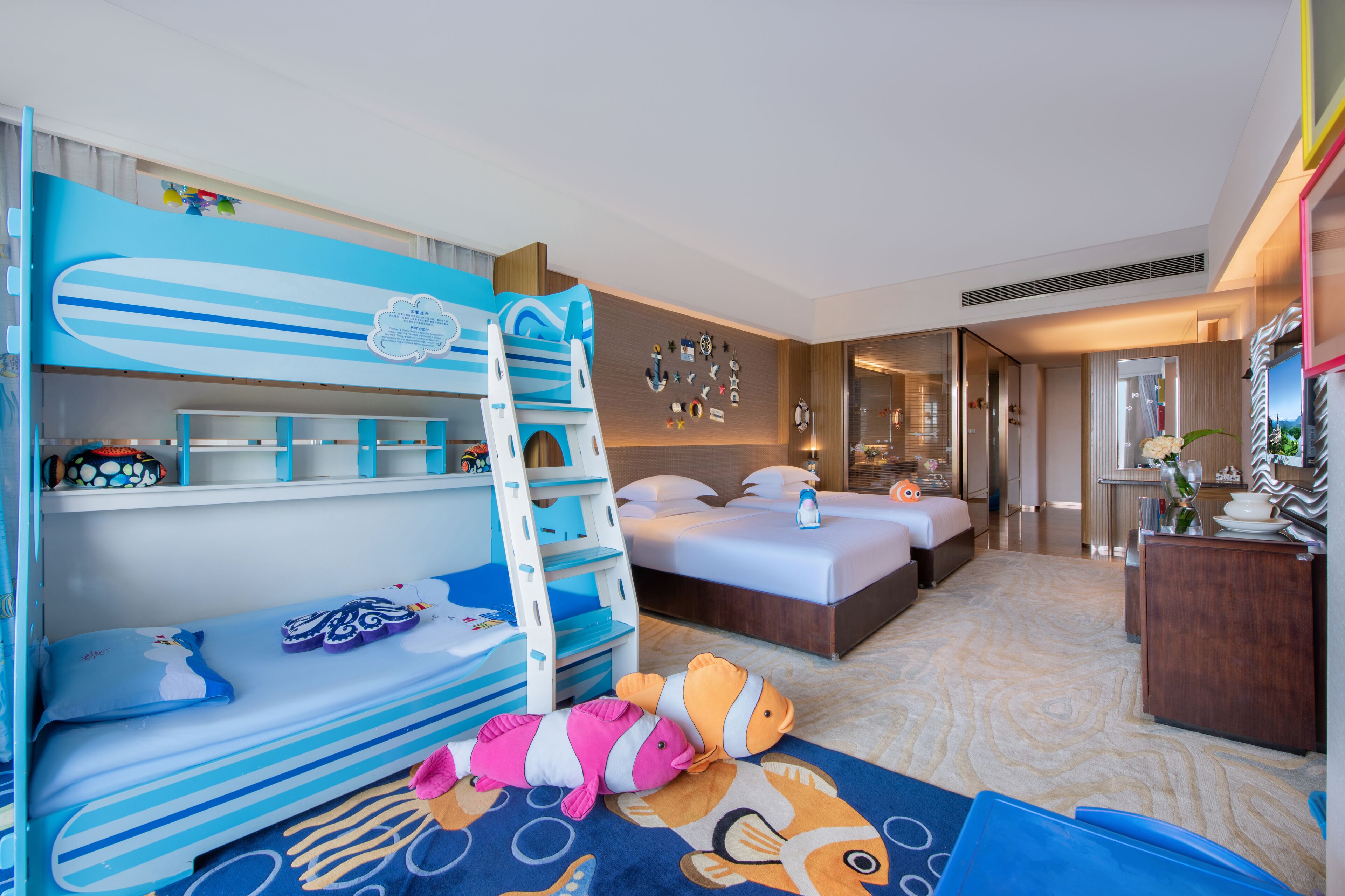 Une chambre d’hôtel avec des lits superposés, un lit, un bureau et une salle de bain.