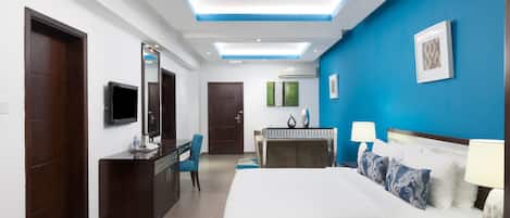 A modern hotel room with a large bed, a desk, a chair, and a TV.
