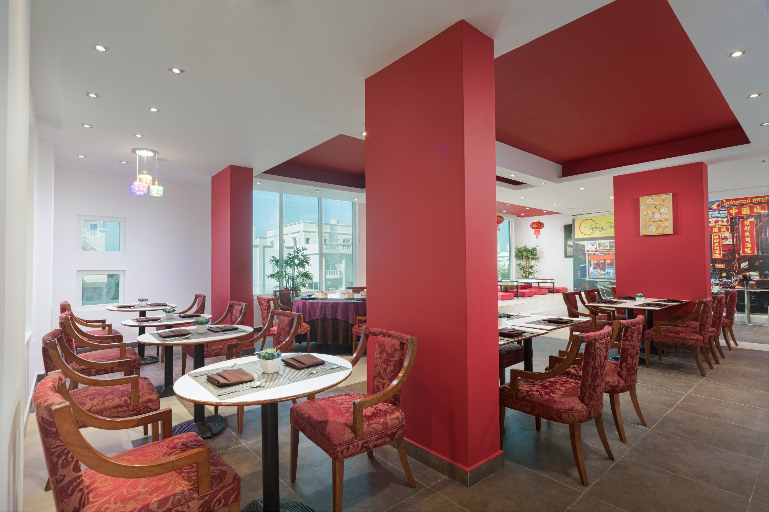 A restaurant with red accents, round tables, and chairs.