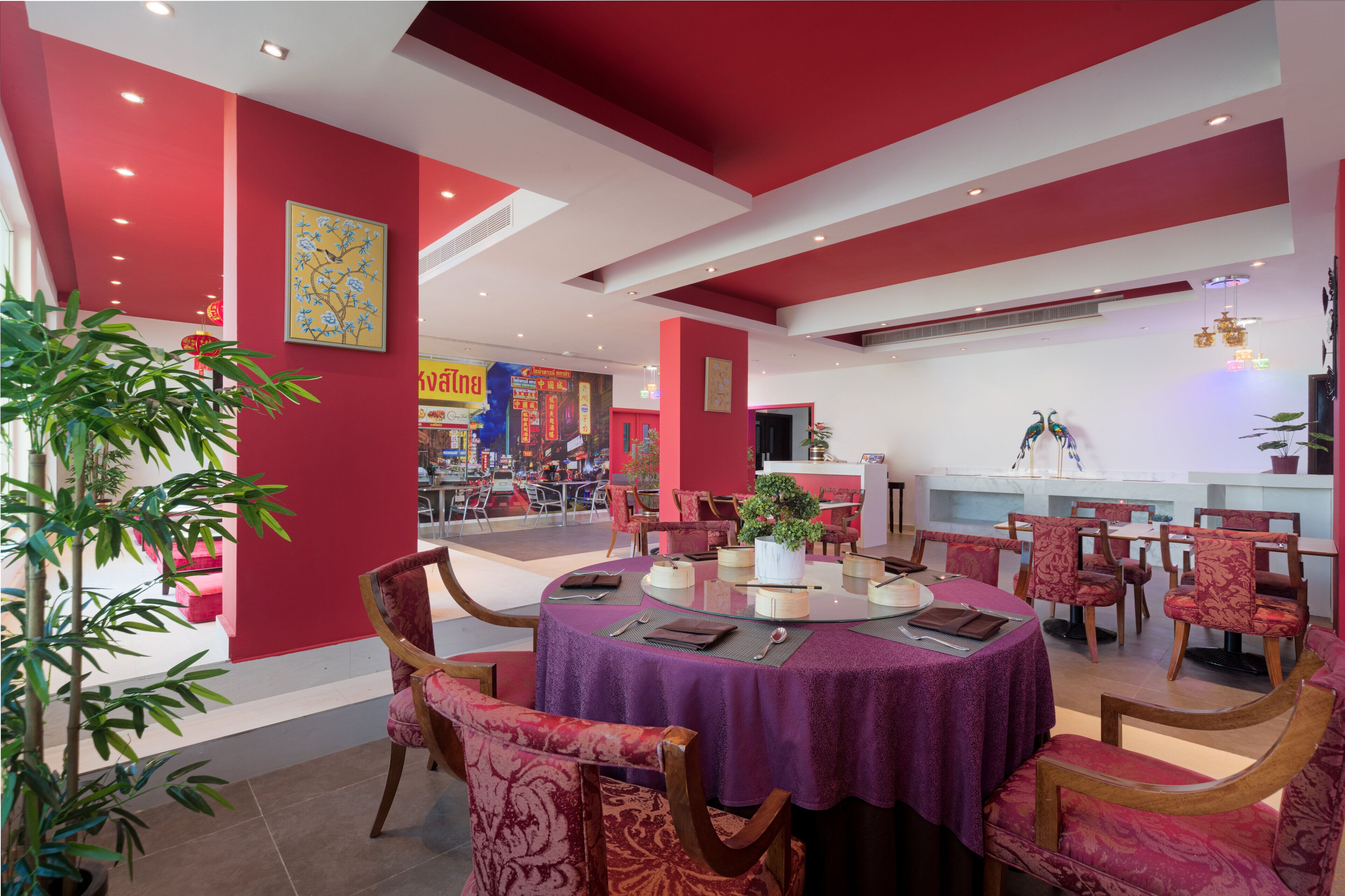 A dining area with round tables, red walls, and potted plants.