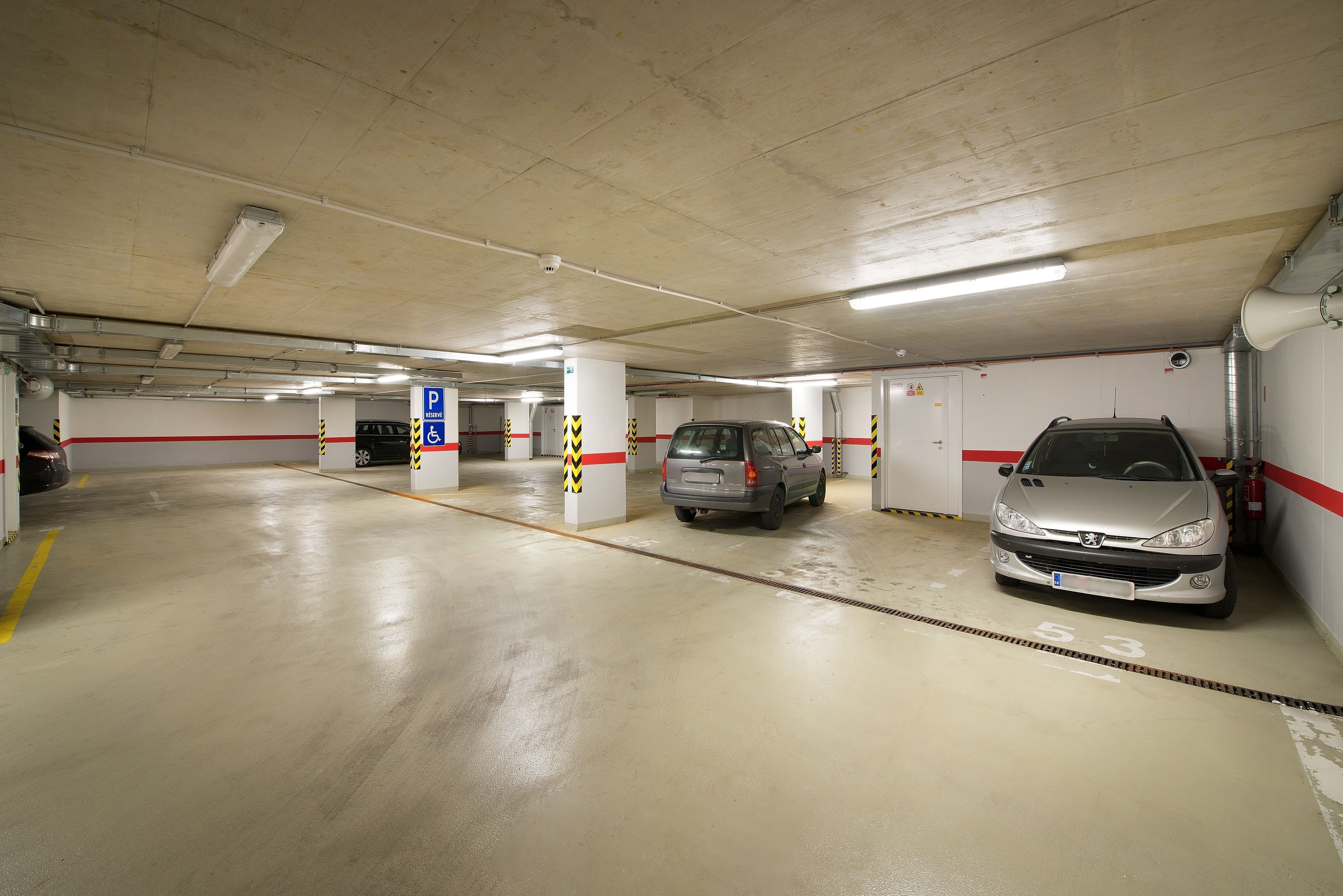 A multi-level parking garage with clear signage, including a handicapped parking area, and a vehicle parked in a designated spot.
