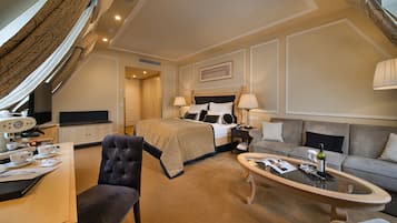Een hotelkamer met een bed, een bank, een salontafel, een bureau met een computer en een televisie.