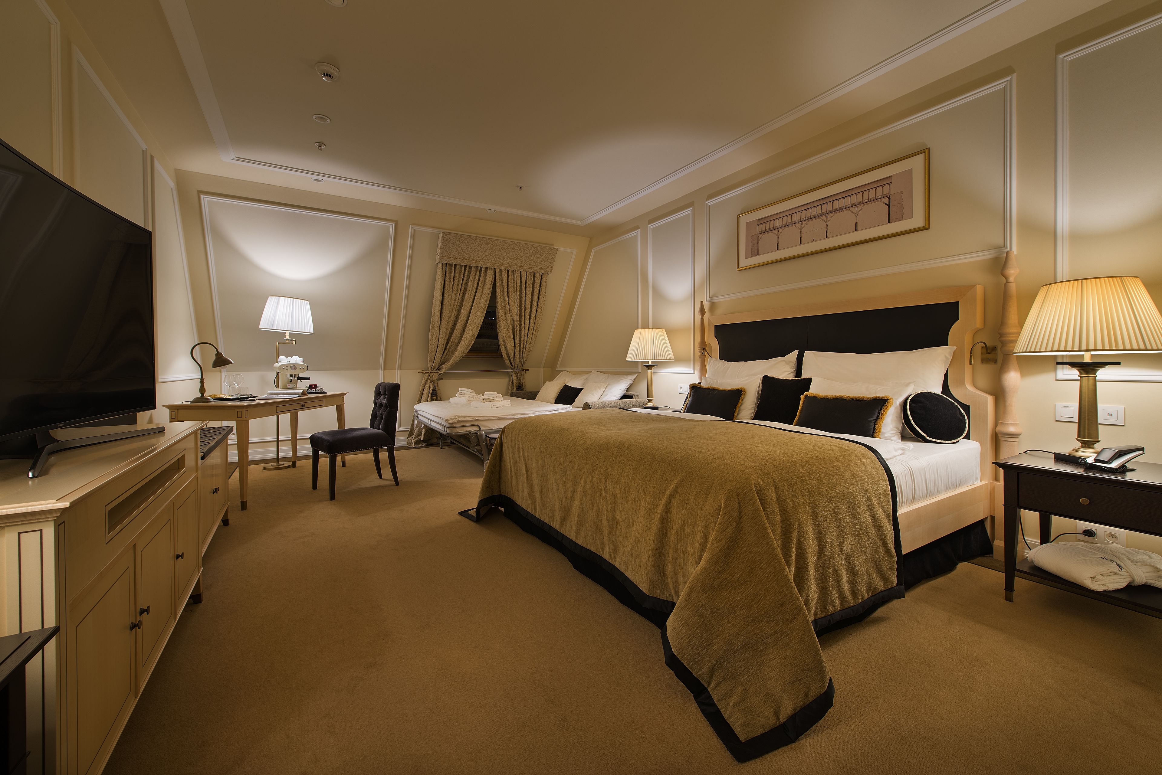A hotel room with a large bed, a desk, a television, and a chair.