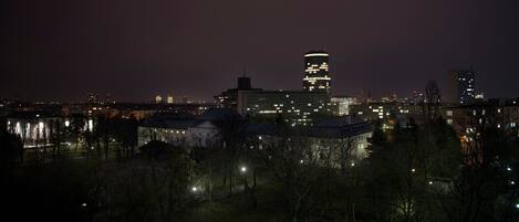 A nighttime cityscape with illuminated buildings and a park area.
