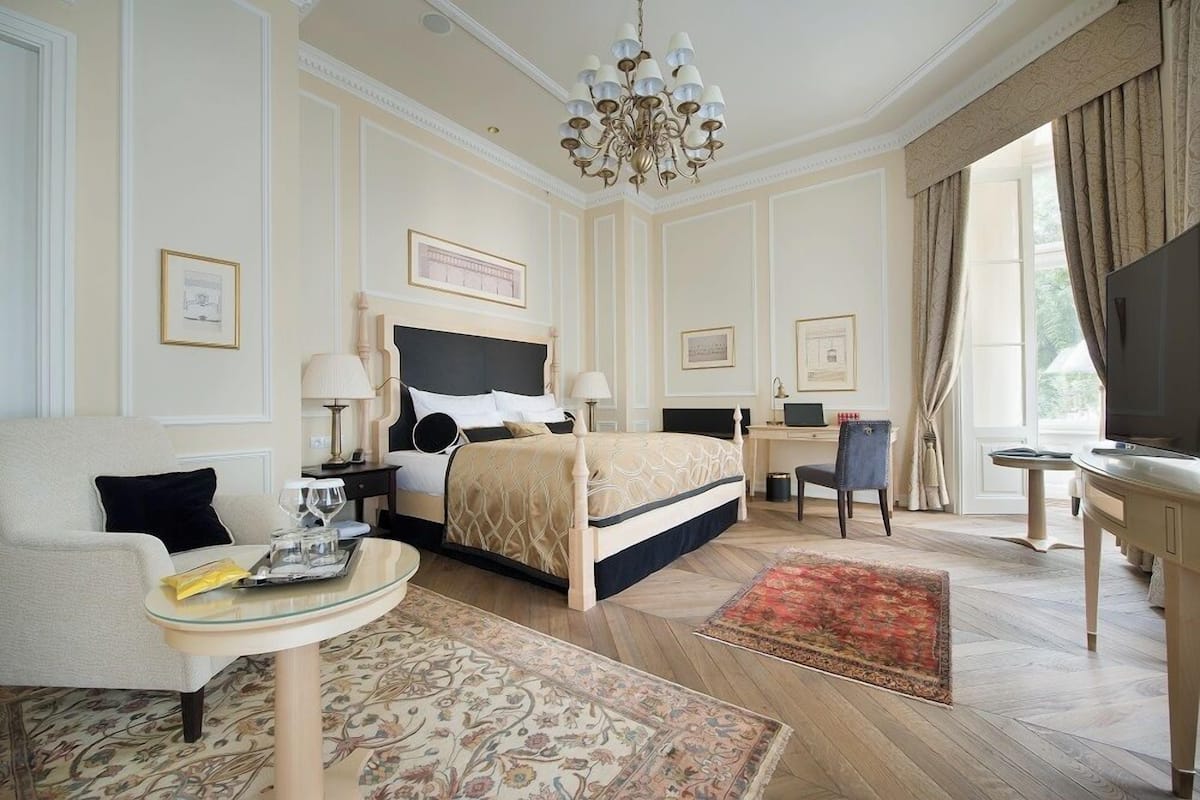 A hotel room with a large bed, a desk, a television, and a seating area with a table and chairs.