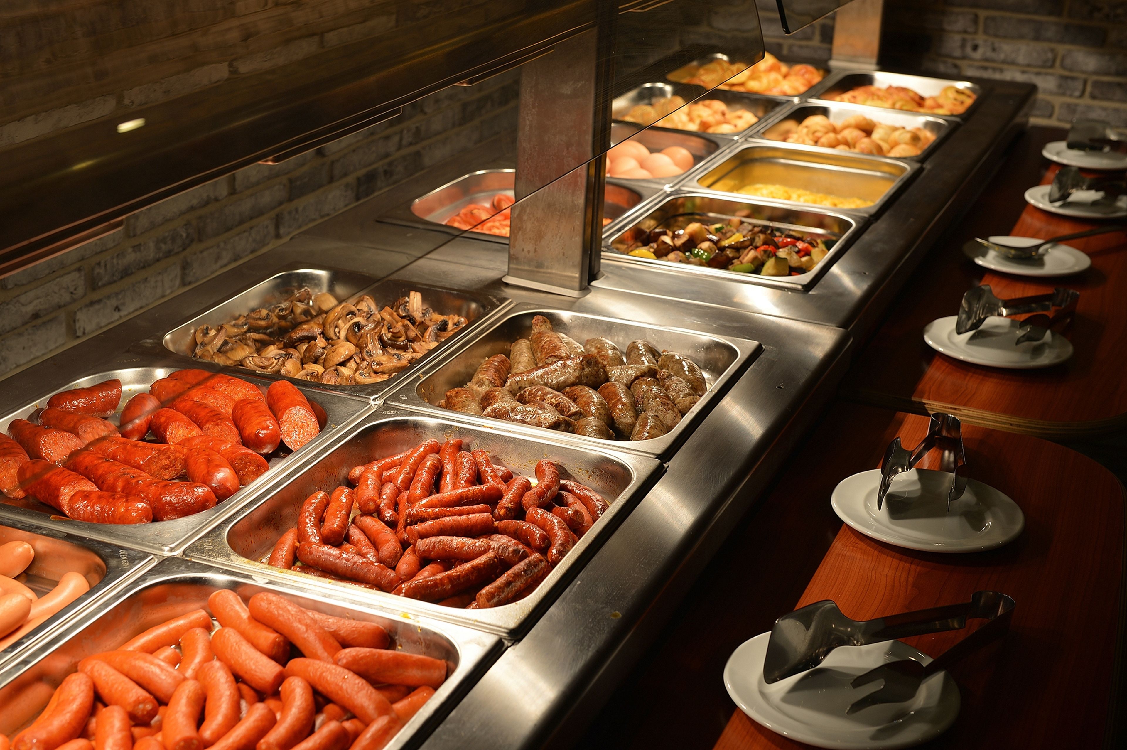 A buffet with various food options including sausages, eggs, and other dishes.