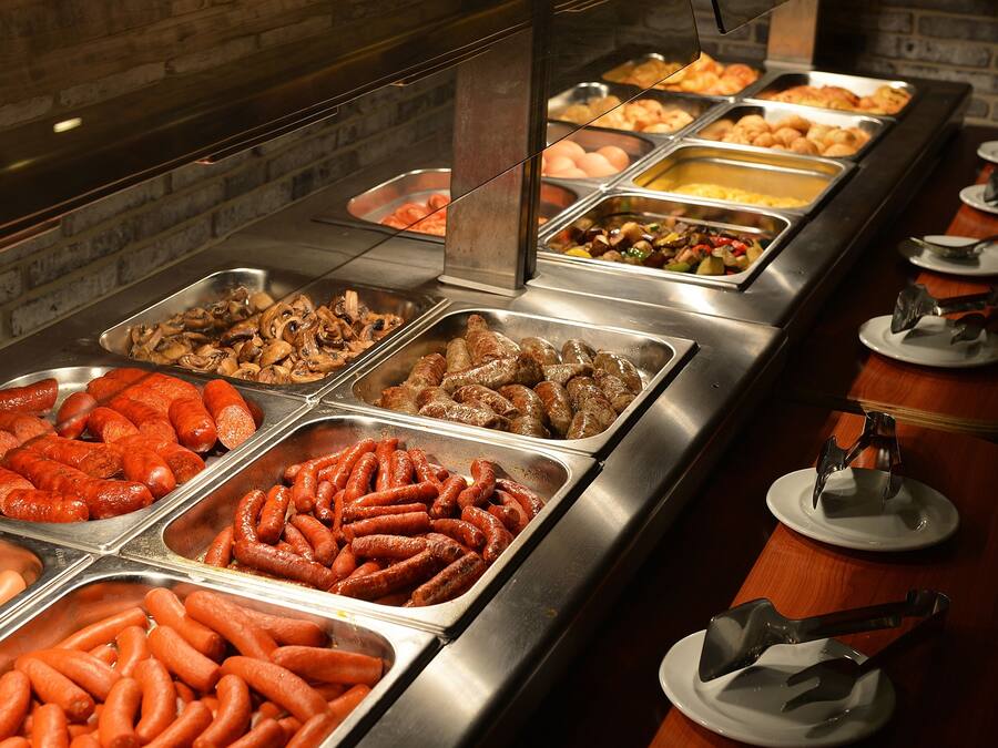 A buffet with various food options including sausages, eggs, and other dishes.