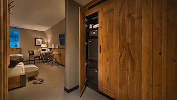 A hotel room with a wooden wardrobe, a bed, a desk, and a chair.