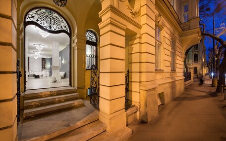 A grand entrance with steps leading to a well-lit interior, featuring a large arched doorway and ornate ironwork.
