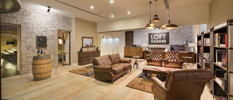 A hotel lobby with a brick wall, leather sofas, a wooden barrel, and a bookshelf.