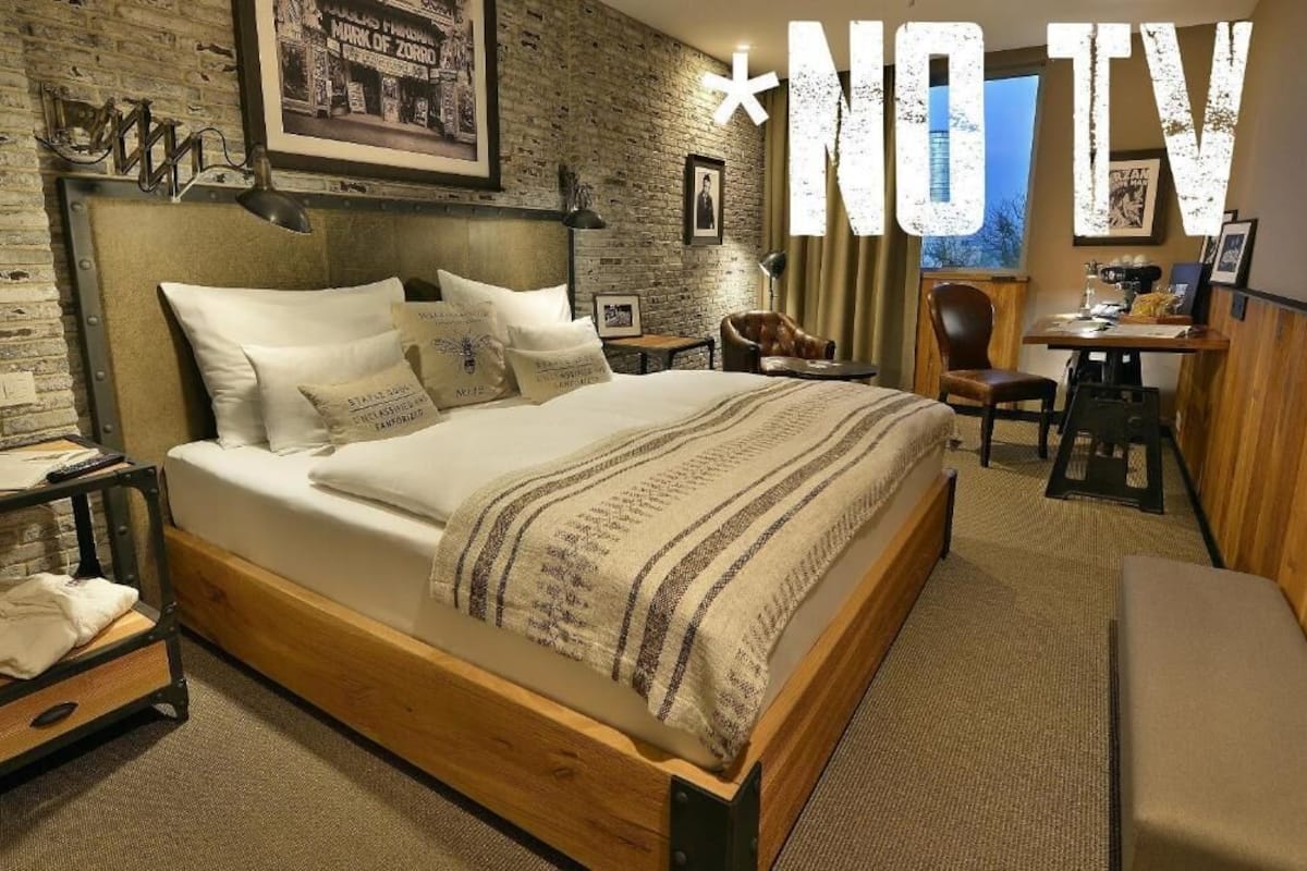 A cozy hotel room with a wooden bed, a desk, and a chair.