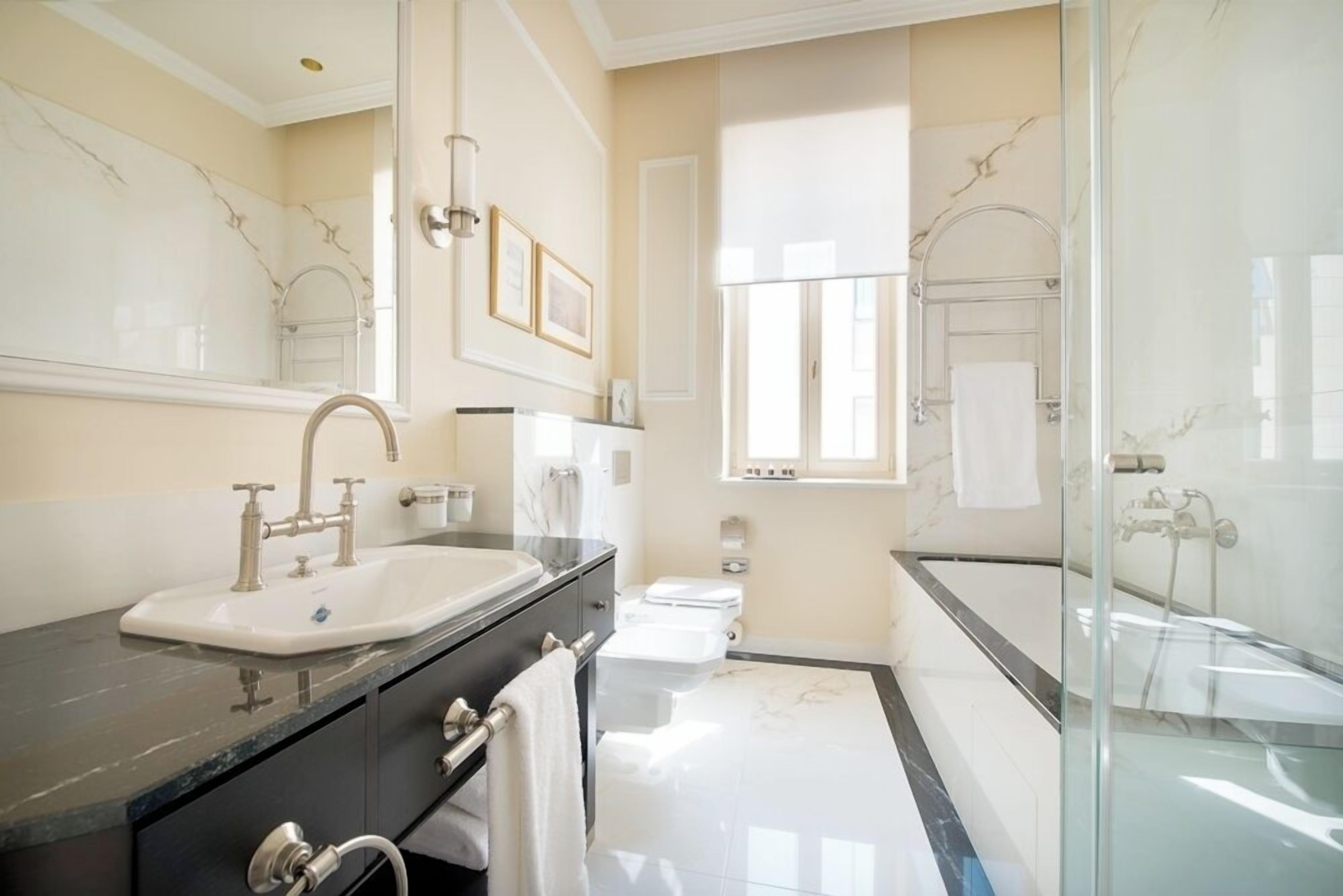 A modern bathroom with a marble sink, a glass-enclosed shower, and a toilet.