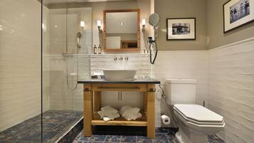 Een moderne badkamer met een douche met glazen wand, een houten wastafelmeubel met een wastafel en een toilet.