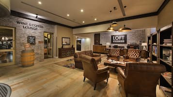 A lounge area with leather sofas, a wooden barrel, and a sign for the wine and coffee lounge.