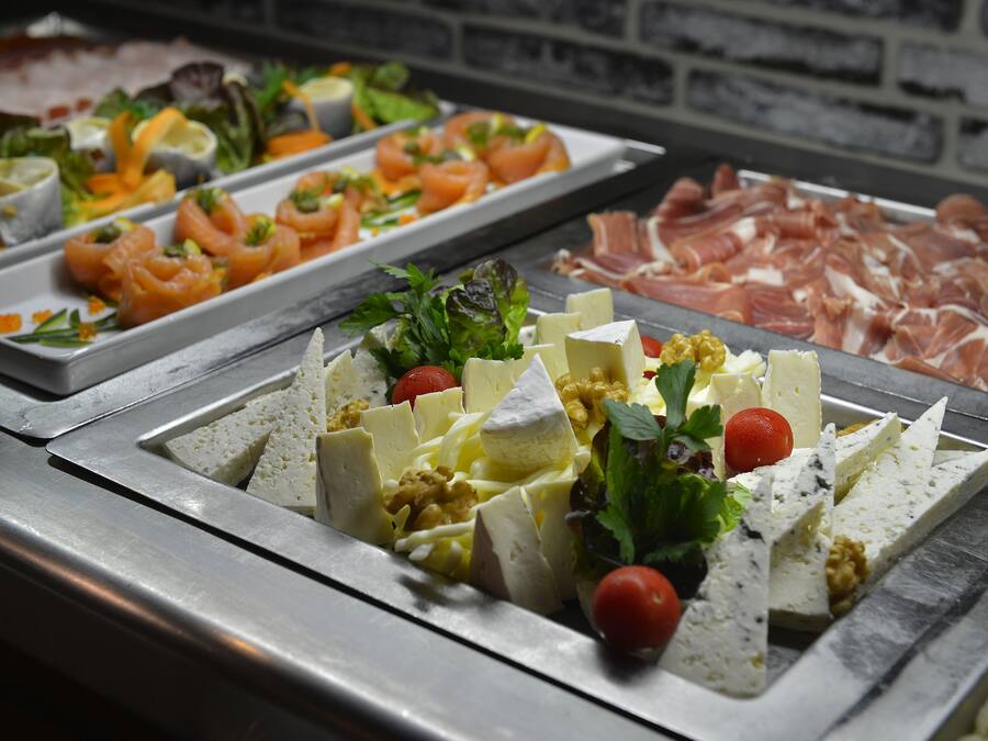 Buffet amb diverses opcions gastronòmiques, incloent carns, formatges i amanides.