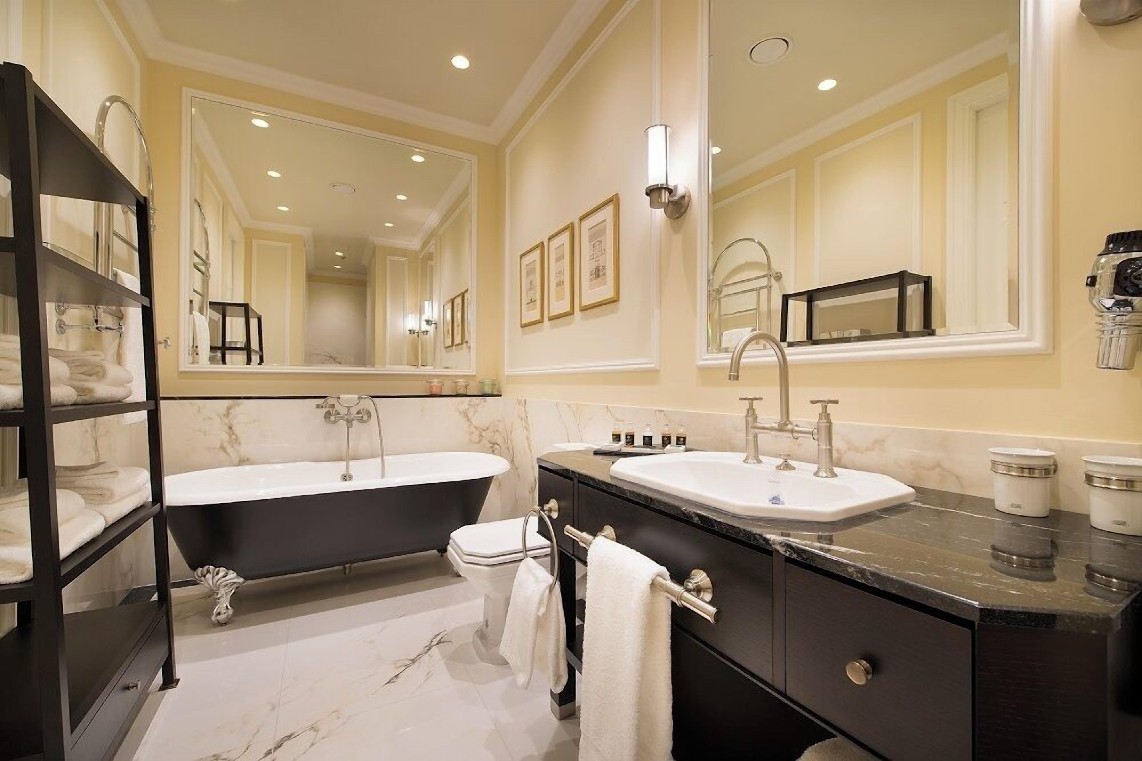 A modern bathroom with a double sink vanity, a freestanding bathtub, and a large mirror.