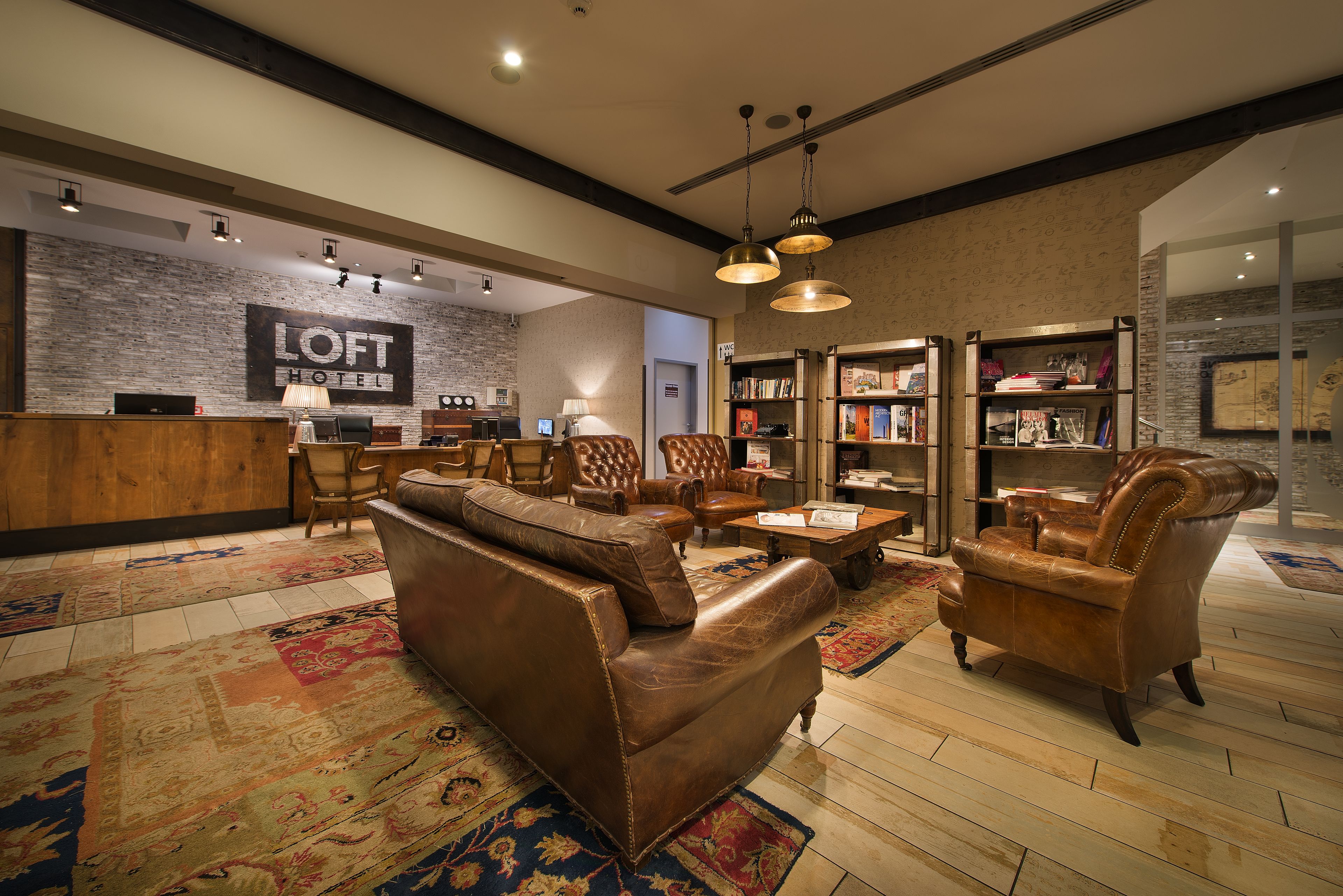 A hotel lobby with leather sofas, a reception desk, and a bookshelf.