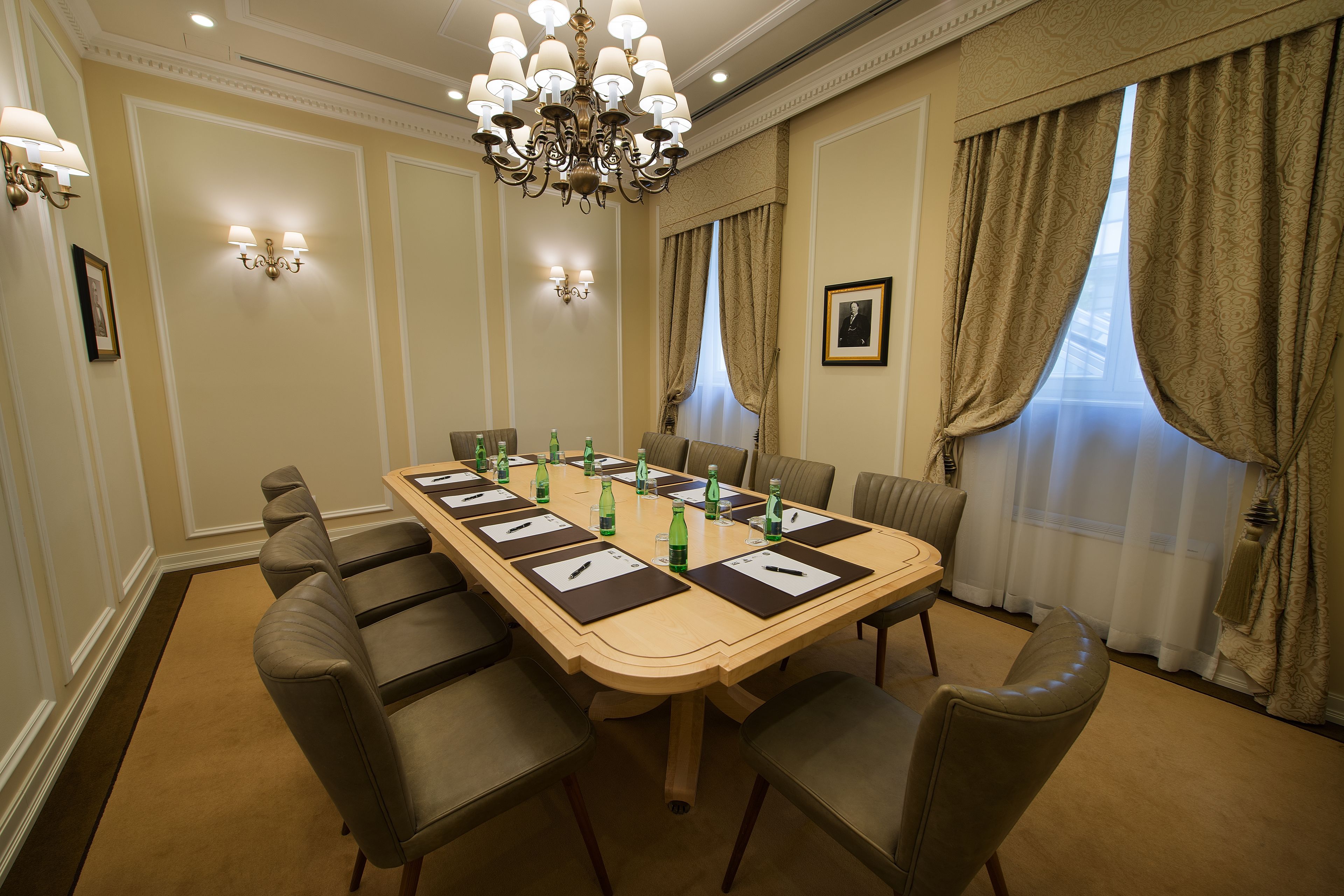 Een vergaderruimte met een lange tafel, meerdere stoelen en een kroonluchter.