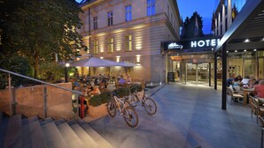 Un hotel con terraza, bicicletas y una escalera que conduce a la entrada.