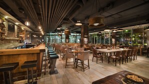 Un restaurante con barra, varias mesas y sillas.