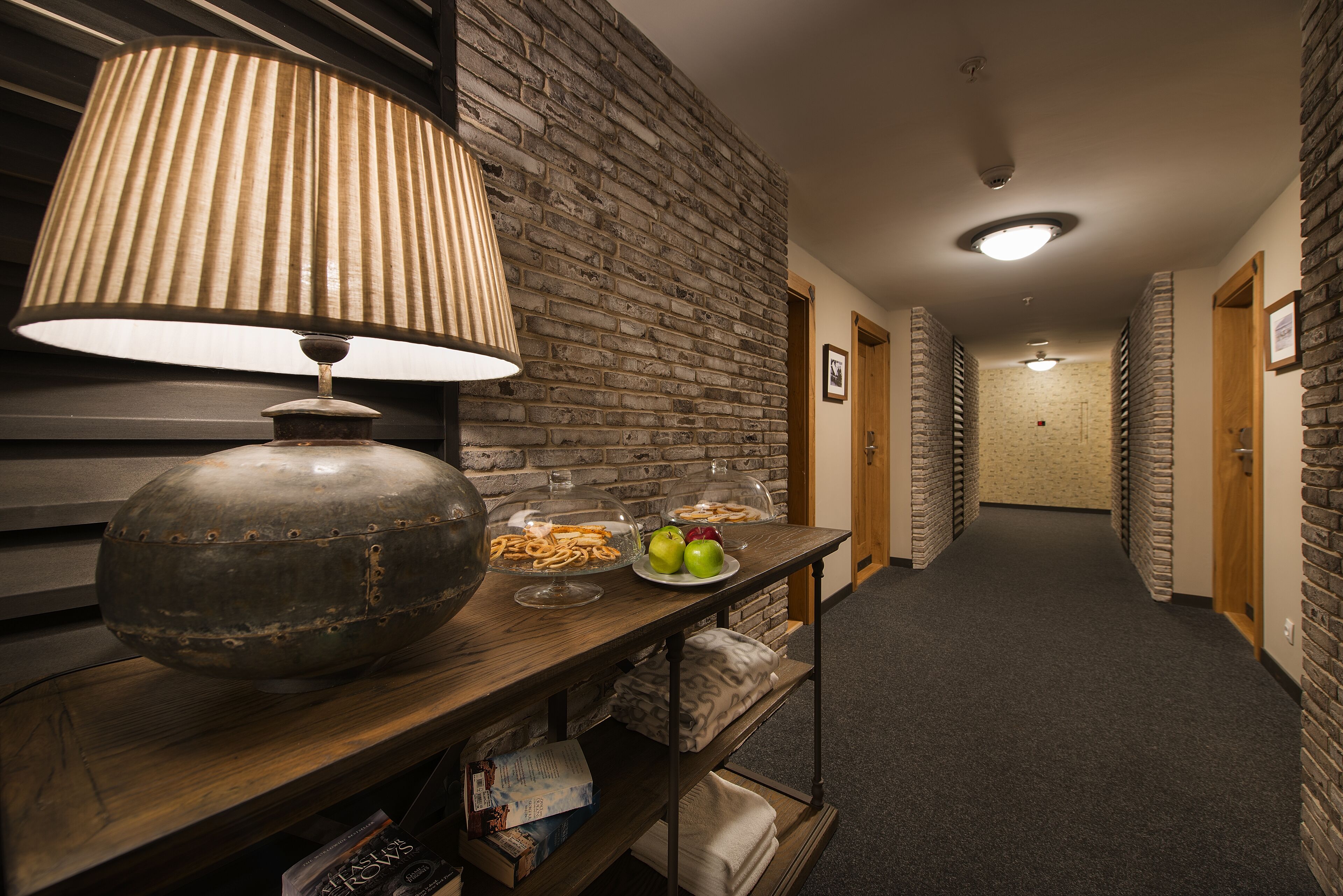 A hallway with a wooden table displaying snacks, a lamp, and a decorative bowl.