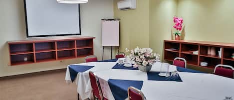 A conference room with a large table, chairs, a projector screen, and a whiteboard.