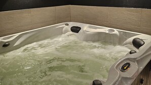 Un jacuzzi con agua corriendo, rodeado de paredes oscuras y una lámpara.