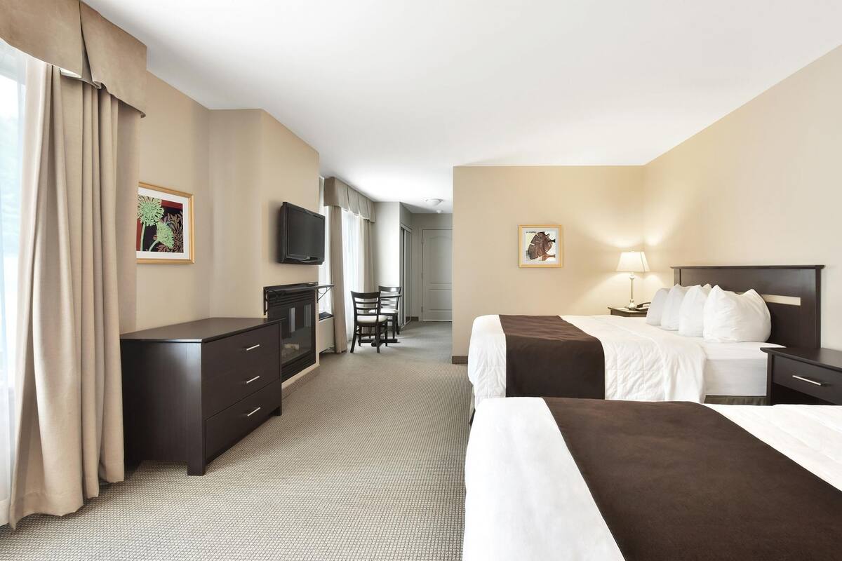 Una habitación de hotel con dos camas, un escritorio, un televisor y una silla.
