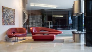 A modern lobby with a red sofa, a glass wall, and a spiral staircase. - Best Western Plus 93 Park Hotel (Bogotá)