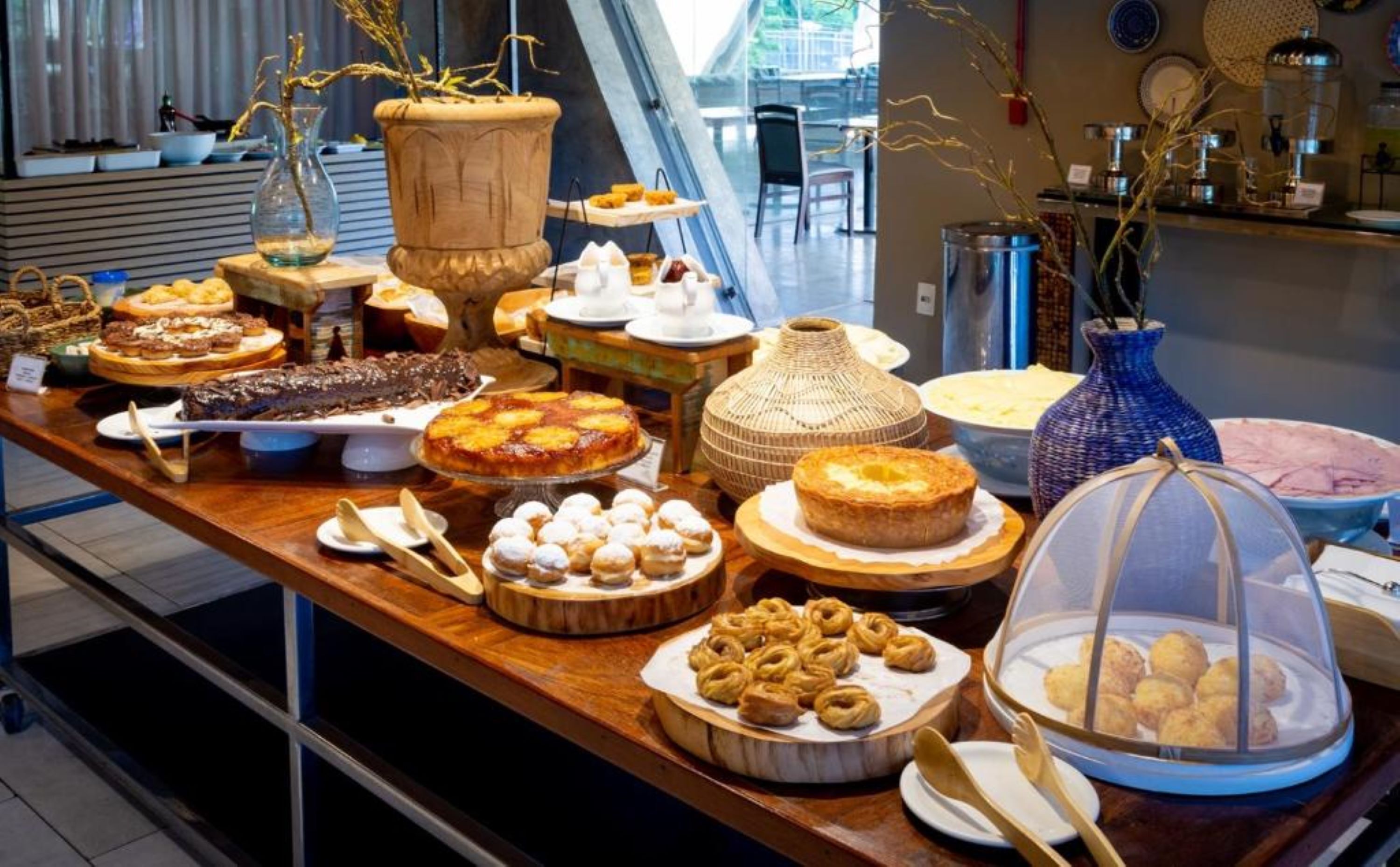A buffet with various dishes and desserts, including cakes and pastries, displayed on a wooden table.