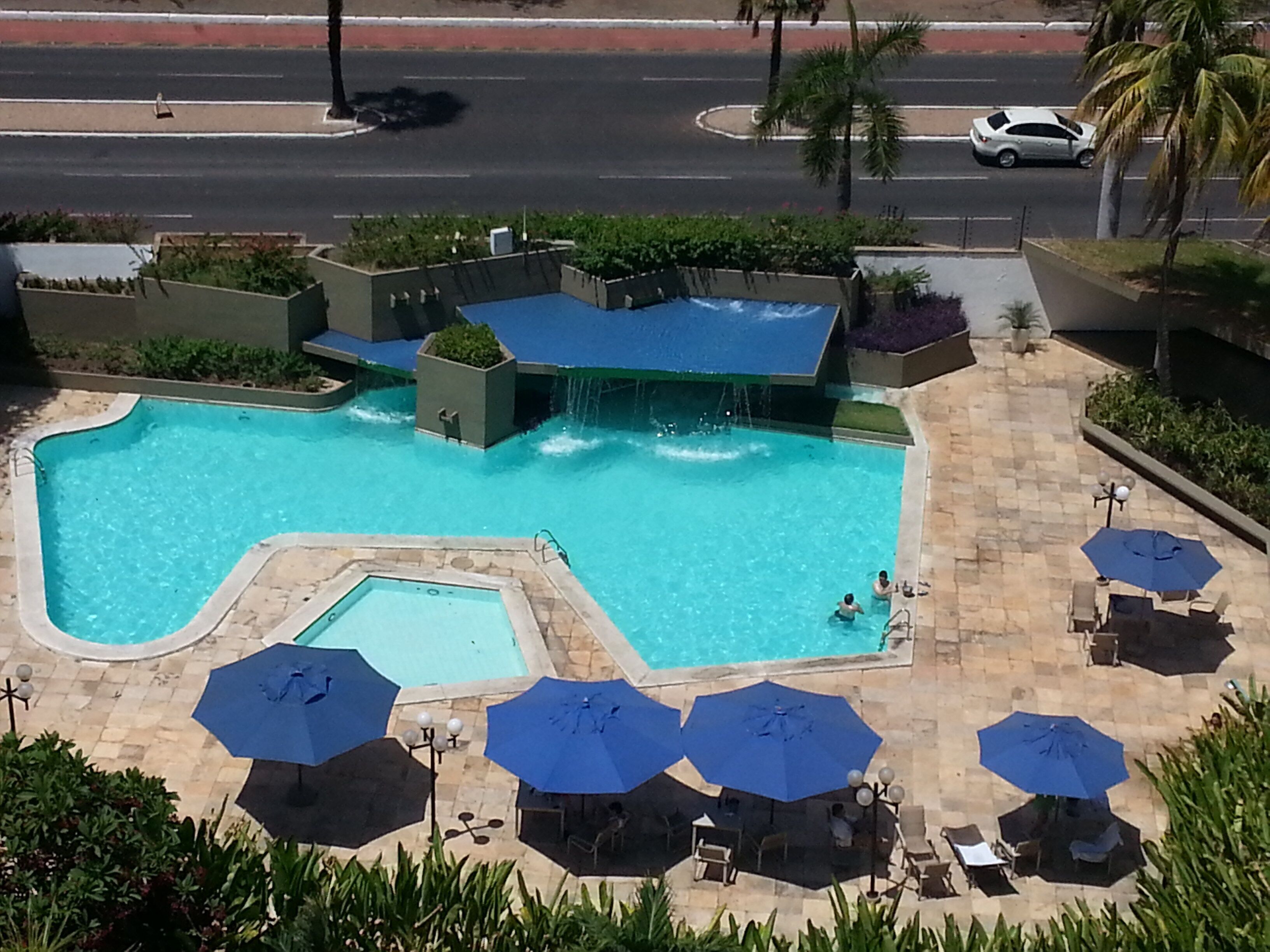 Una piscina al aire libre, sombrillas, sillones reclinables de piscina