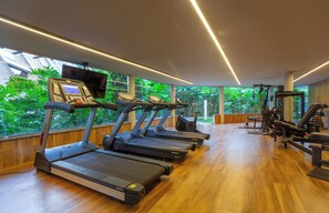 Un gimnasio con cintas de correr, máquinas de pesas y una pantalla de televisión.