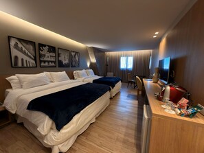 A hotel room with two beds, a desk with a TV, and a minibar.