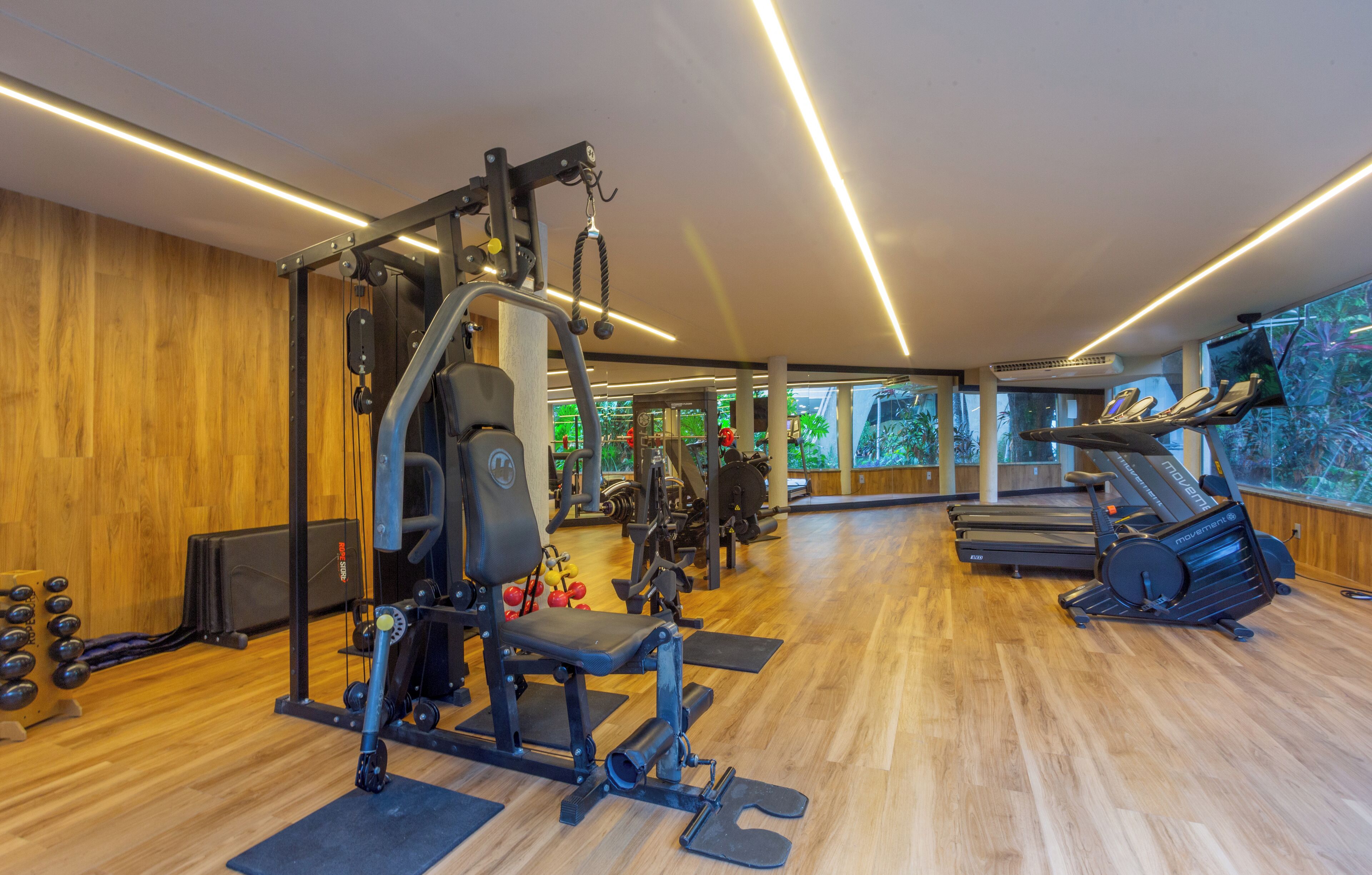 Un gimnasio con diferentes equipos de ejercicio, una cinta de correr y una máquina de remo.