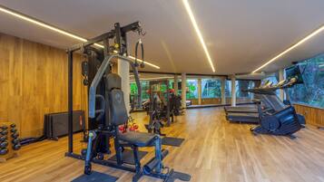 Un gimnasio con diferentes equipos de ejercicio, una cinta de correr y una máquina de remo.