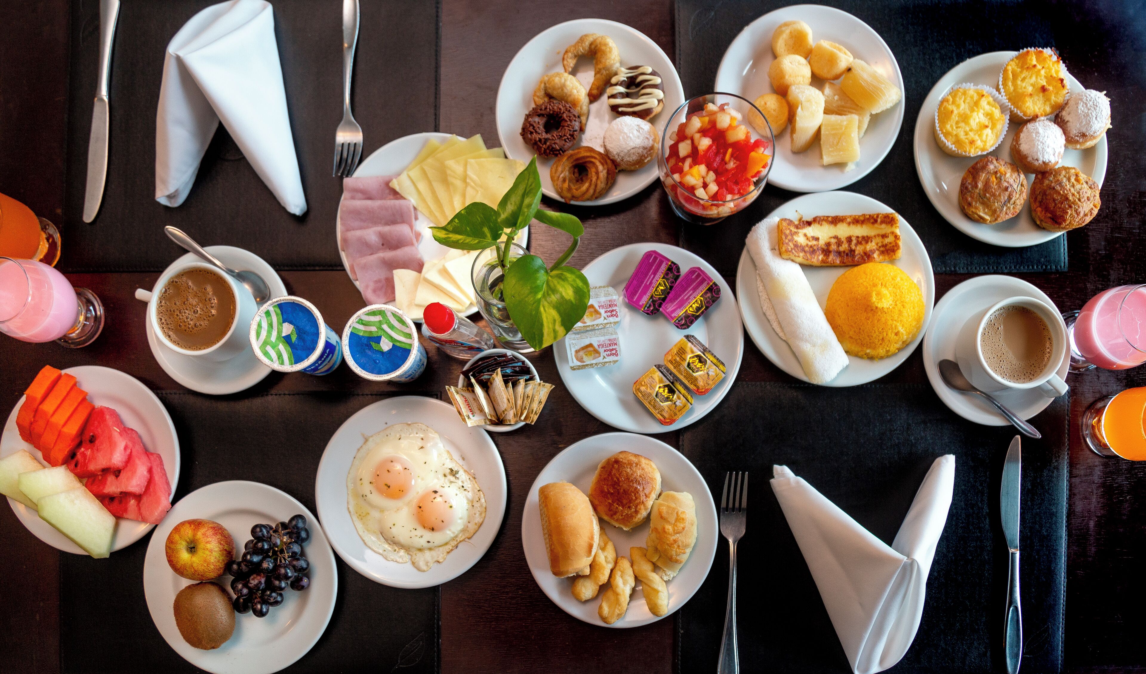 Un bufé de desayuno con diversos platos, como huevos, bollería y frutas.