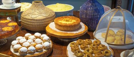 Une variété de produits de boulangerie présentés sur des planches en bois et dans une vitrine, notamment des pâtisseries et des gâteaux.